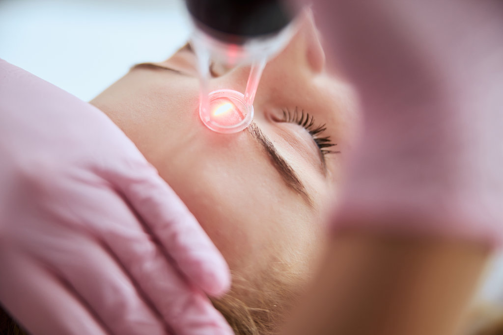 Cropped photo of a qualified lady dermatologist in latex gloves performing a facial resurfacing procedure