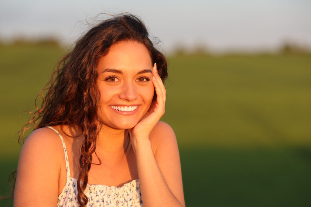 Happy beautiful woman posing in a field at sunset