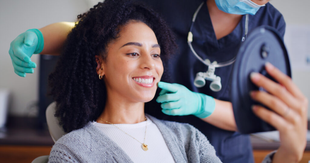 Woman smiling at mirror during a dental checkup visit